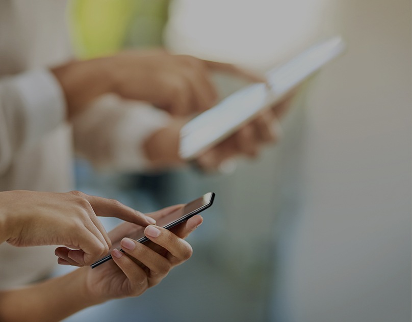 En närbild från sidan visar en person som vidrör sin smartphoneskärm med pekfingret.