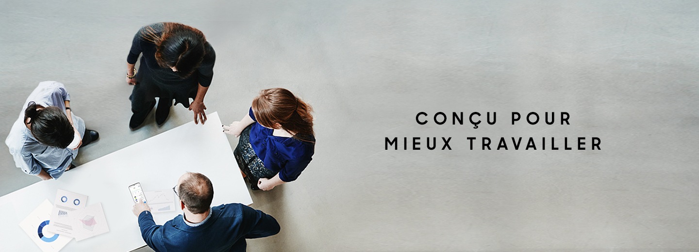 Quatre personnes debout autour d'une table avec des graphiques sur le dessus, avec un homme pointant l'écran du Galaxy S20 Ultra et un texte disant "Conçu pour mieux travailler".
