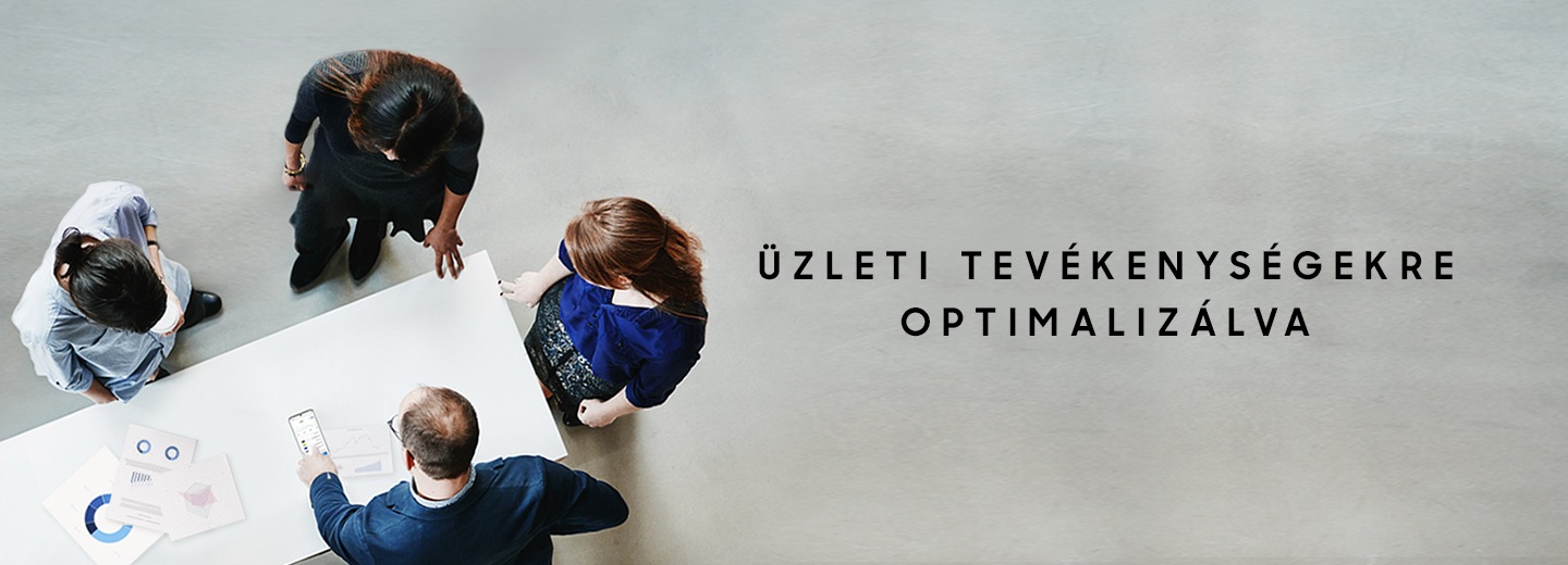 Négy férfi áll körül egy táblázatokkal megpakolt asztalt, miközben egyikük egy Galaxy S20 Ultra 5G készülék képernyőjére mutat, „Optimized for Business” (üzleti célokra optimalizálva) felirattal.