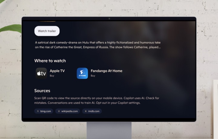Copilot thuộc Microsoft. Toàn cảnh màn hình hiển thị biểu tượng micro kèm dòng chữ "Bạn đang muốn xem gì hôm nay?" Một ngón tay nhấn vào nút micro. Một người nói: "Này Copilot! Tôi đang muốn xem một bộ phim lãng mạn, vui nhộn, có gợi ý nào không?" Màn hình hiển thị nhiều nội dung liên quan đến tình cảm, hài hước và đối thoại dí dỏm. Trang chi tiết hiển thị phần tóm tắt nội dung cùng thông tin về nơi có thể xem chương trình đó.