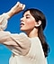 A young woman wearing a white blouse is shown from her left profile with a Galaxy Buds Live earbud in her left ear.