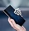 A hand holds up a Galaxy smartphone device that has a glass-like layer floating in front of the screen. A white Samsung Knox logo floats in front of the glass-like layer.