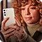 A close up image of a woman with curly ginger hair, holding a Galaxy smartphone to take a picture of the foreground.