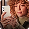 A close up image of a woman with curly ginger hair, holding a Galaxy smartphone to take a picture of the foreground.
