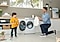 A boy and his father are laughing about the son’s crayon-stained shirt. The father is kneeling in front of the QuickDrive™, holding out a fresh and clean white t-shirt that just came out of the wash for the boy to change into.