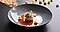 A round, glazed ceramic coupe of grey-blue carefully holds a layer of tomato coulis at the center, over which stands tall, a choux pastry hatted with caramel and seeds. The plate is perfected by a garnish of three popped corn kernels around the choux.