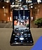 "هاتف Galaxy Z Flip4 مفتوح على سطح بحافة مع فتح تطبيق الكاميرا وعرض مشهد المدينة على شاشة الهاتف. "