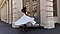 Une femme debout devant une vitrine tourne dans sa robe blanche dans un mouvement de va-et-vient et au ralenti