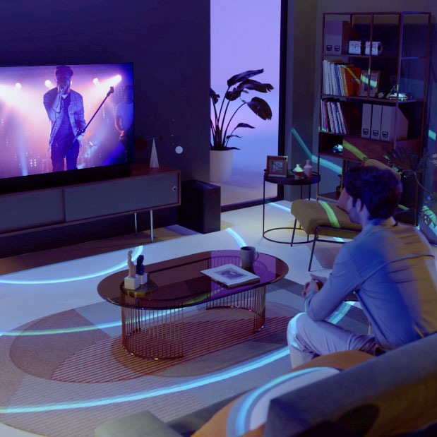 Um homem assiste a uma actuação musical. Há ondas sonoras que são projectadas da TV.