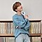 j-hope i BTS, duke qëndruar në këmbë dhe duke parë lart me Galaxy S20 në dorë, gjenden tre rafte të mbushura me regjistrime muzikore prapa tij