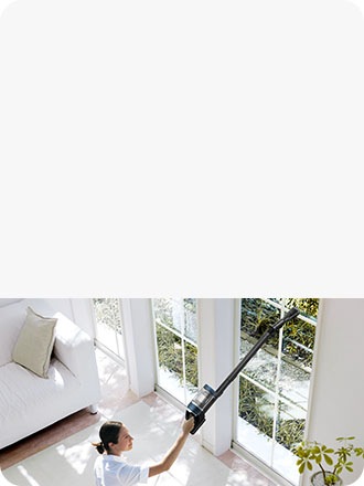 Një grua fshin një dritare të lartë me një Bespoke JET.