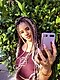 Una mujer con cabello trenzado de colores se toma una selfie frente a un árbol.