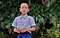 El joven personaje principal de Kids of Paradise usando un uniforme escolar, está parado frente a unos árboles.