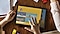 A tablet on a table surrounded by papers and LEGO blocks. A child’s hands are nearby and their right hand is touching the tablet screen. Onscreen is the LEGO App UI, showing different kinds of entertainment your child can experience.