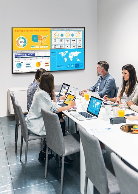 People are sitting in a conference room and watching data from their laptops by QxB. QxB is divided into 4 screens, each showing different information on one screen.