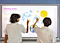 two boys sitting at interactive display drawing