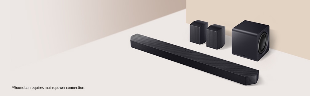 A soundbar with a subwoofer and two rear speakers are laid out on the floor.