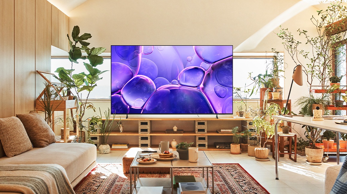 A 98 inch Supersize TV is mounted on a wall in a living room displaying nature.