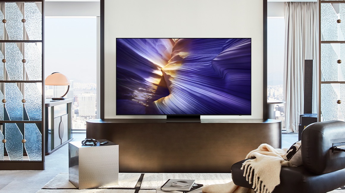 A 98 inch Supersize TV is mounted on a wall in a living room displaying water.