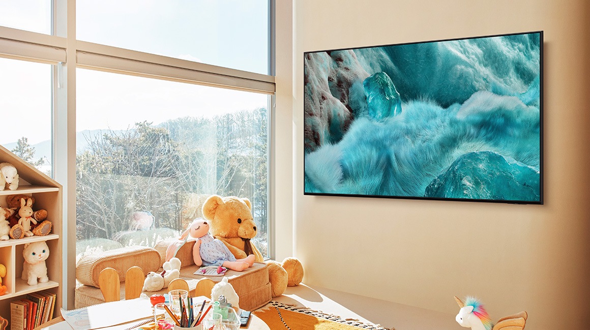 A 98 inch Supersize TV is mounted on a wall in a living room displaying the ocean.