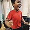 Boy in a red shirt smiling and raising his arms in the air the joy