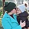 Mother kissing her baby boy in the cheek and boy smiling