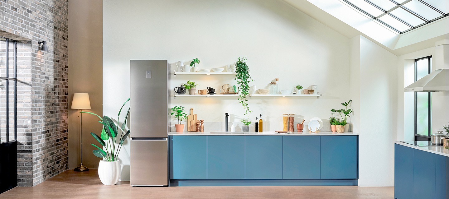Een Samsung-koelkast RB7300T met een nieuwe onderbouwvriezer met SpaceMax™ staat tussen een groene plant en het cadetblauwe aanrecht. En dan toont de video de beste temperatuur om groente in de koelkast in te bewaren en zo je vershoudruimte te maximaliseren.