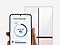 Met een koelkast op de achtergrond houdt een hand een Galaxy-smartphone vast met daarop de UI van de SmartThings-app AI Energy Mode.