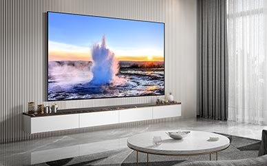 Een 98 inch Supersize TV is gemonteerd aan de muur in een huiskamer. Op het scherm wordt water weergegeven.