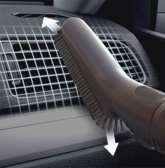 De soft dusting brush van een Samsung Jet-stofzuiger reinigt de ventilatieroosters op het dashboard van een auto