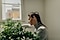 Une femme accroupie arrose une plante