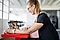 Une femme assise à un bureau rouge utilise une tablette pour discuter en vidéo avec quatre personnes.