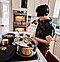 Femme aux cheveux courts cuisinant dans une cuisine moderne.