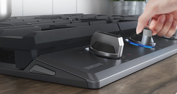 cooktop de cor cinza escuro com uma mão girando o botão de ligar