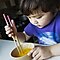 Cute Little boy holding chopsticks stir egg in bowl
