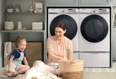 Mom and daughter organizing clothes in front of a Samsung washing machine