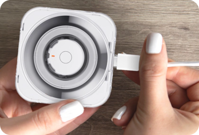 Hand connecting a USB-C cable to a Galaxy Ring's transparent charging case.