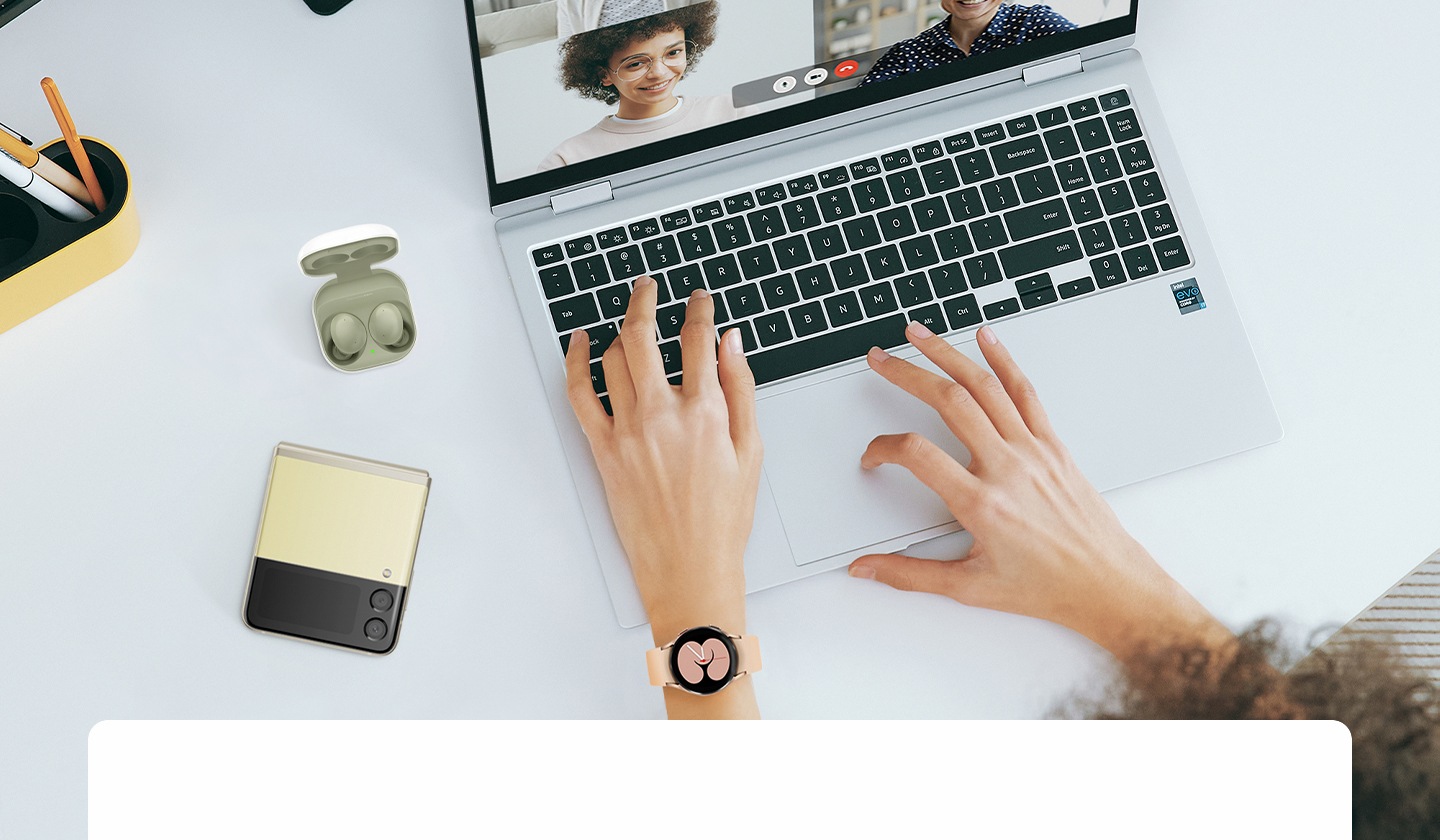 A home office desk featuring Galaxy smartphone, Galaxy Buds, Galaxy Watch and Samsung laptop making a video call