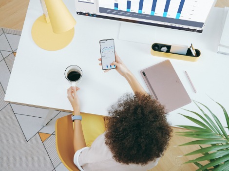 A girl working with Samsung DeX while holding a cup of coffee.