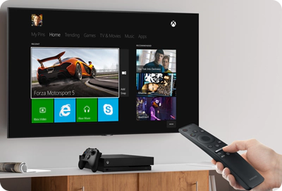A Samsung TV remote controlling an Xbox console displayed on a TV screen.