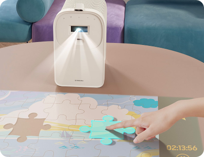 Le Premiere 5 projetant un jeu de puzzle sur une table, avec un doigt qui interagit avec une pièce par toucher.
