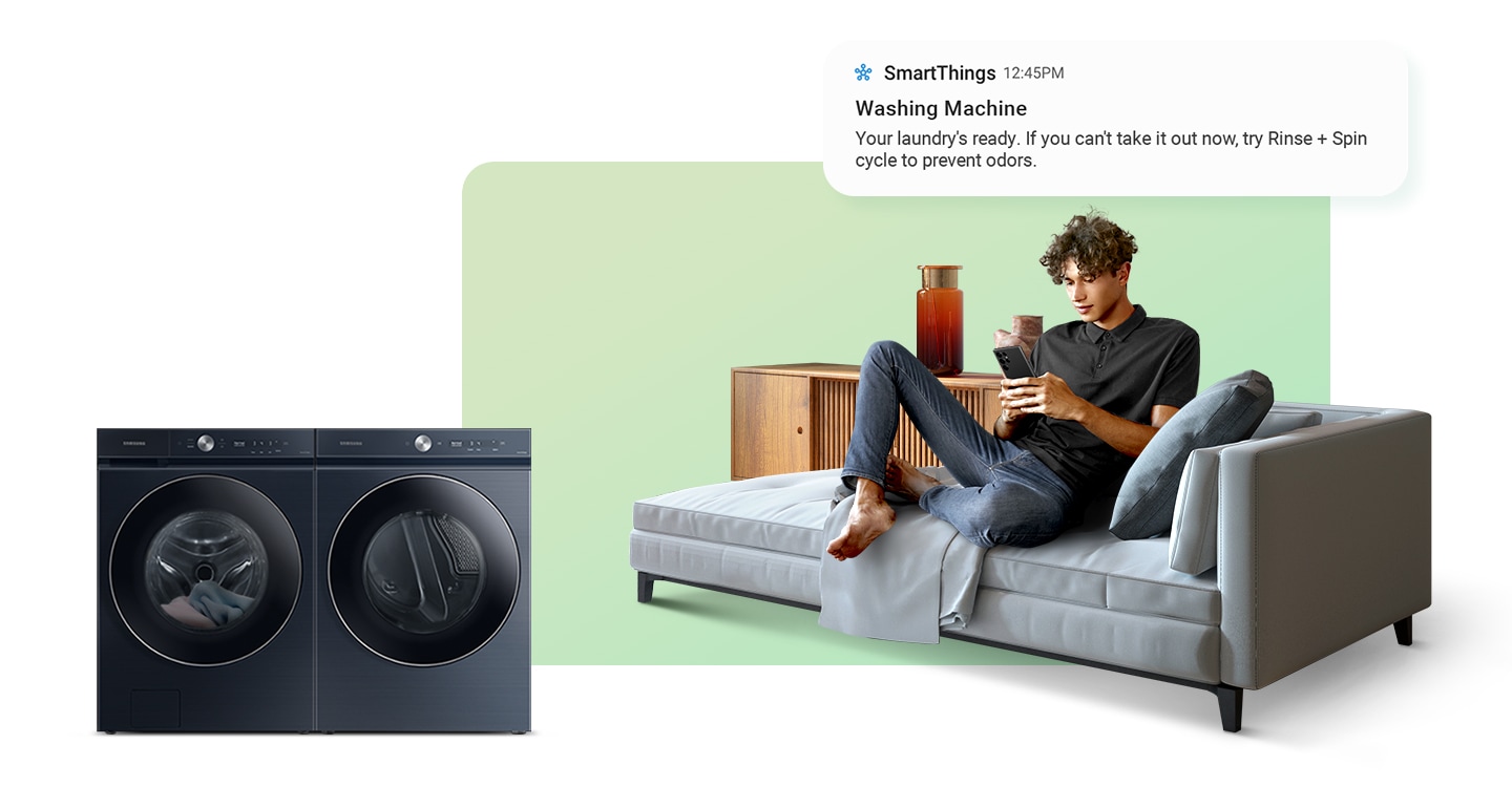 A white Bespoke AI washer and dryer set is placed side by side. To its right is a man lounging on a couch and looking at his smartphone. He receives a notification 'Your laundry's ready. If you can't take it out now, try Rinse + Spin cycle to prevent odors.'