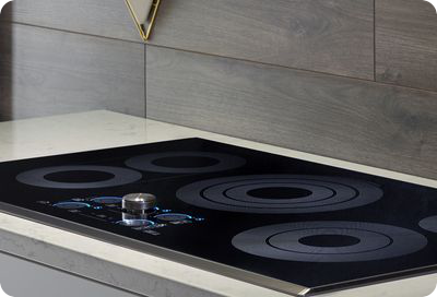 Une plaque de cuisson électrique Samsung moderne, avec une surface noire élégante et des zones de cuisson bleues illuminées, installée dans une cuisine moderne.