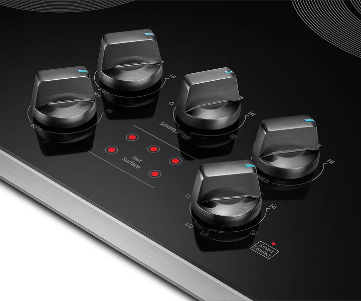 Plaque de cuisson électrique Samsung avec cinq boutons de commande métalliques dotés d’indicateurs bleus et un panneau de contrôle affichant des voyants rouges pour différents niveaux de chaleur.