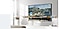 A wall-mounted The Frame displays Pont Neuf, Paris by Auguste Renoir. Other artwork can be selected from the menu below. The option to add the artwork to favorites is highlighted.