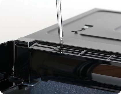 Removing the top vent screw from a Samsung microwave with a Phillips head screwdriver.