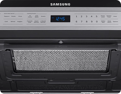 Close-up of the grease filter case under a Samsung microwave with the PUSH label centered above the filter.