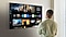 A person stands before a Smart TV, navigating through a myriad of content and OTT options.