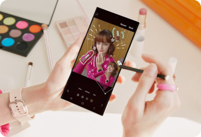 Une personne utilise un Samsung Galaxy Z Fold, en utilisant un style, dans un environnement créatif et coloré, avec des produits de maquillage en arrière-plan.