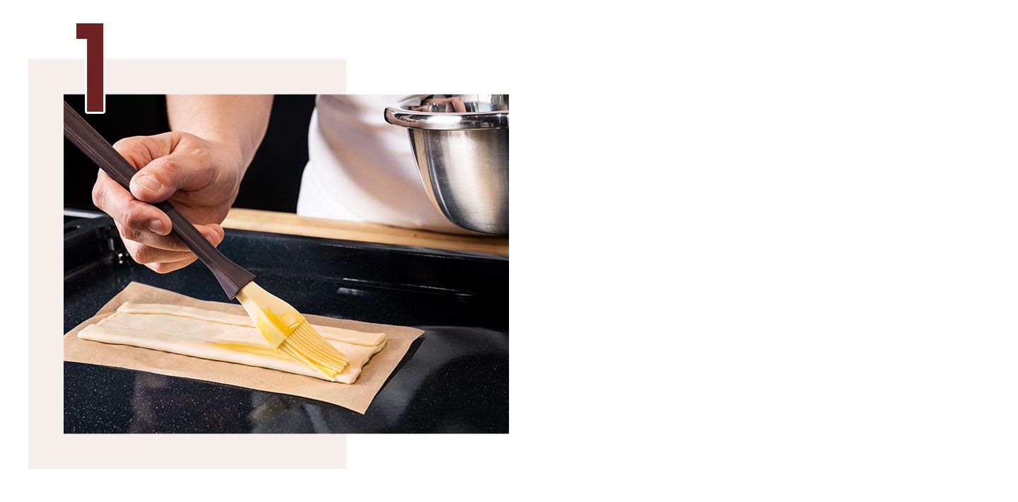 Étape 1. Une main badigeonne soigneusement les côtés d’une pâte avec un pinceau à pâtisserie.